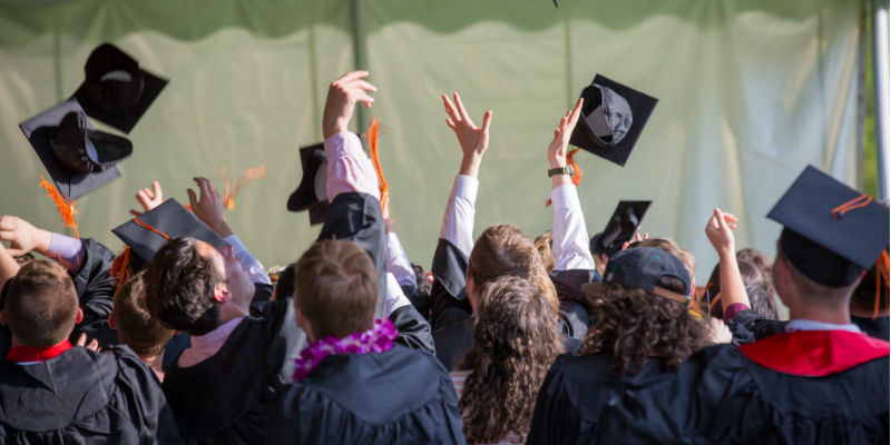 School students throwing hats into the air 