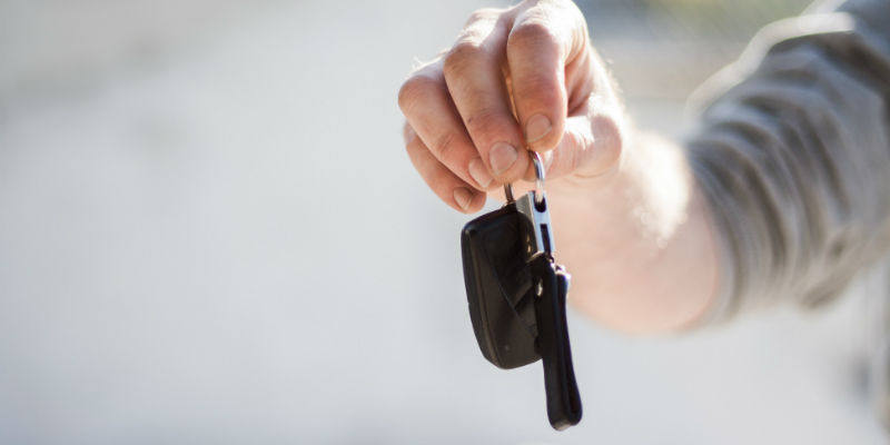 A car dealer holding out car keys