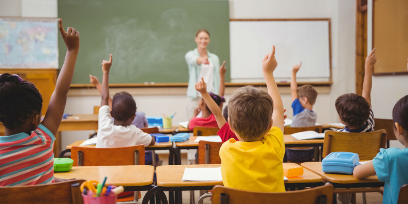 Children raising hands in classroom 