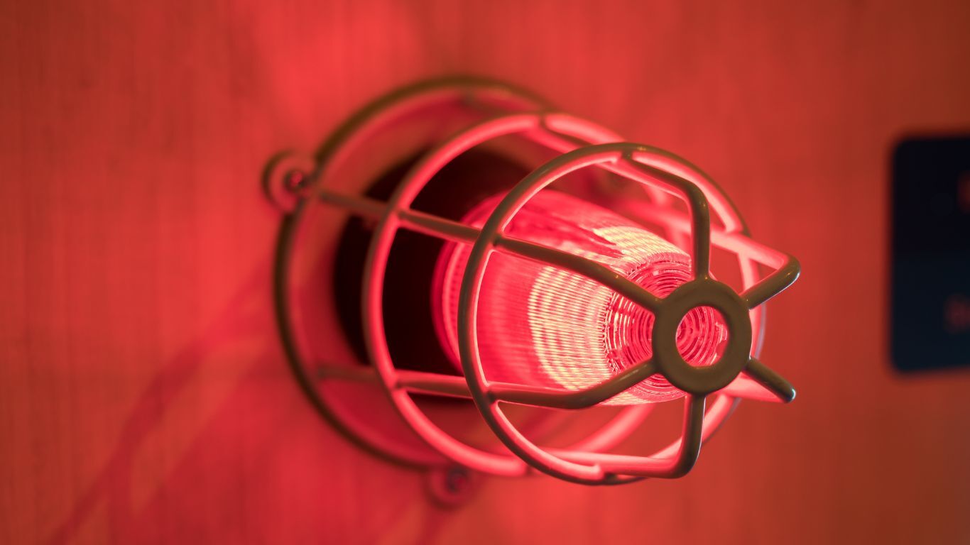 A lit red alarm light on a wall.